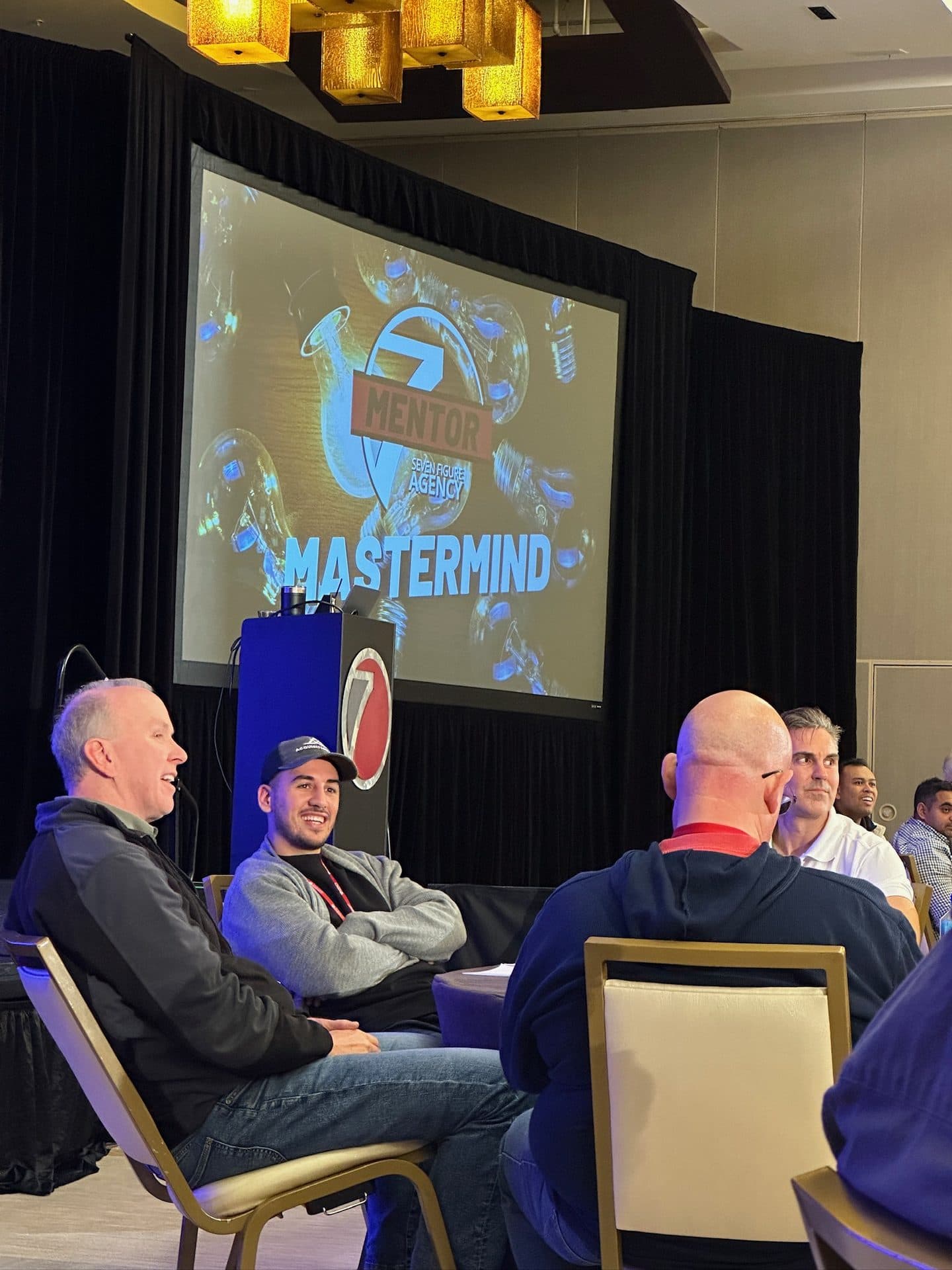 A panel discussion on stage at a mastermind conference