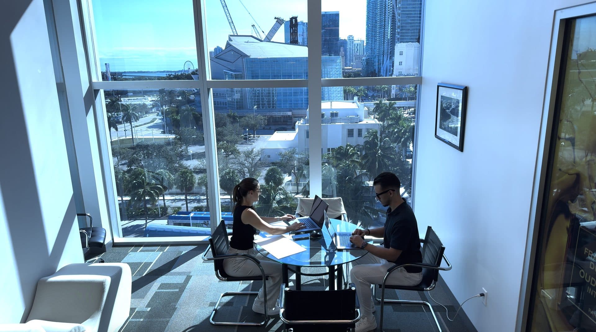 Two of the MYA team working through an account, the Miami skyline behind them